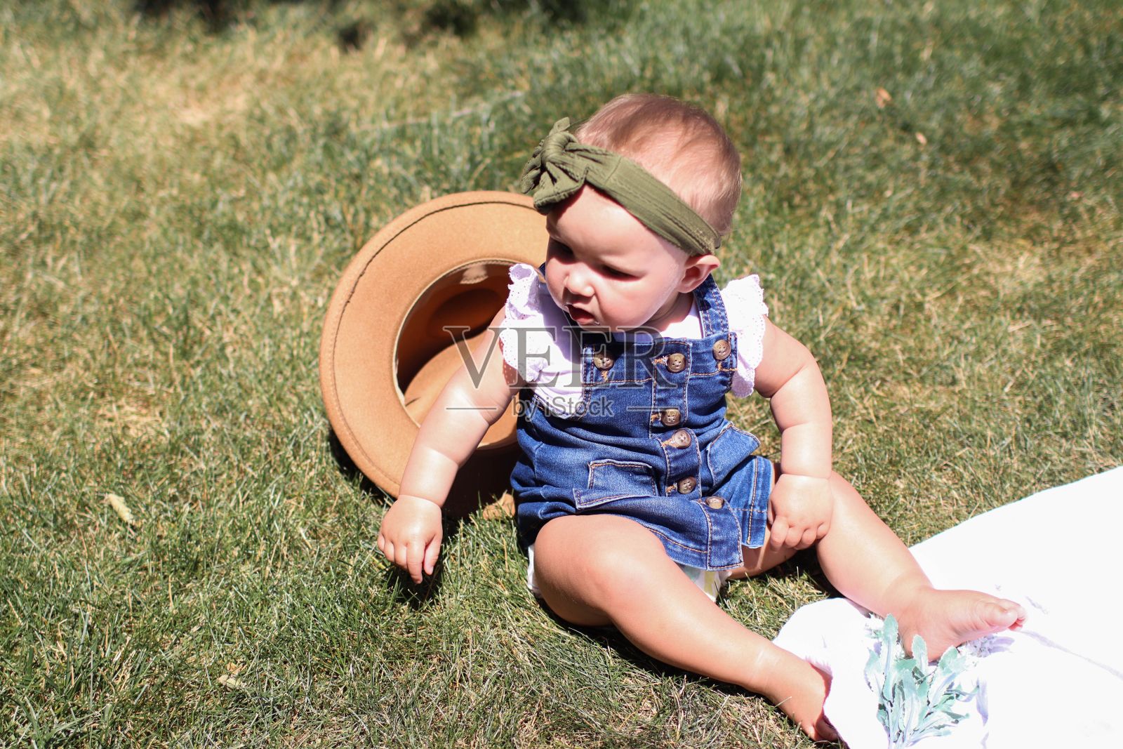 夏天,10个月大的白人婴儿戴着妈妈的帽子照片摄影图片