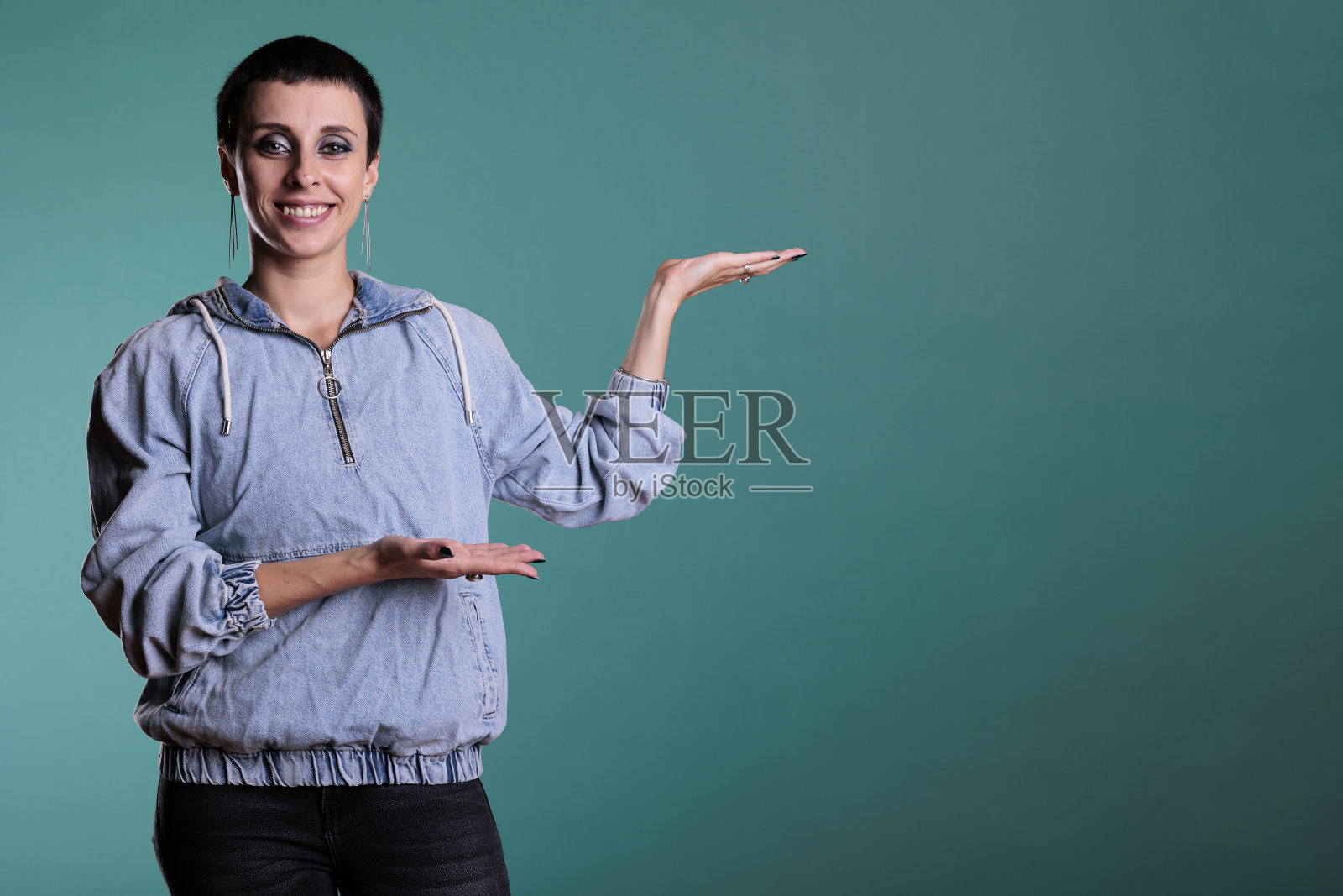 欢快微笑的女人指着右边的工作室广告产品照片摄影图片