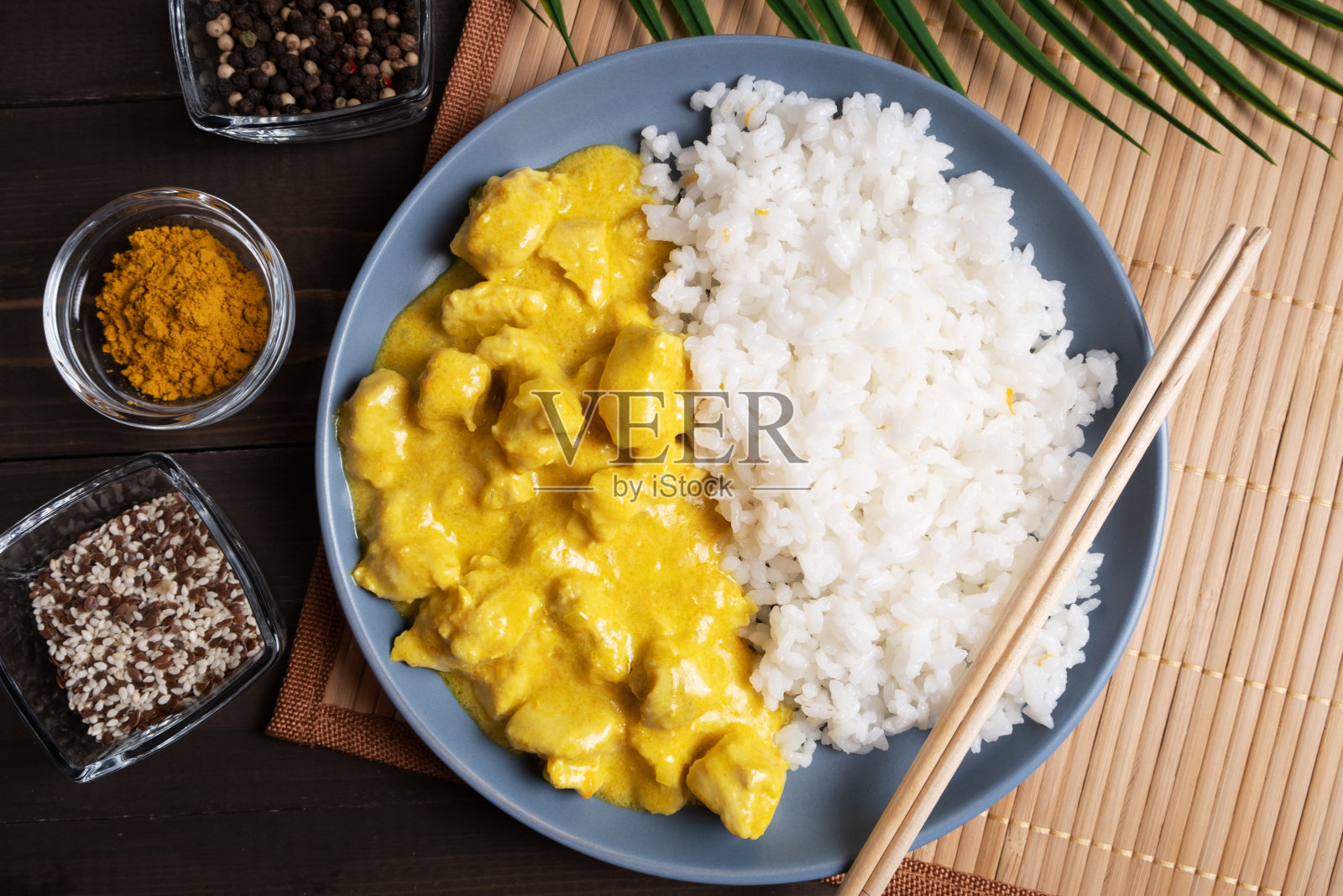 咖喱酱鸡肉米饭,放在蓝色盘子和竹餐巾上。照片摄影图片