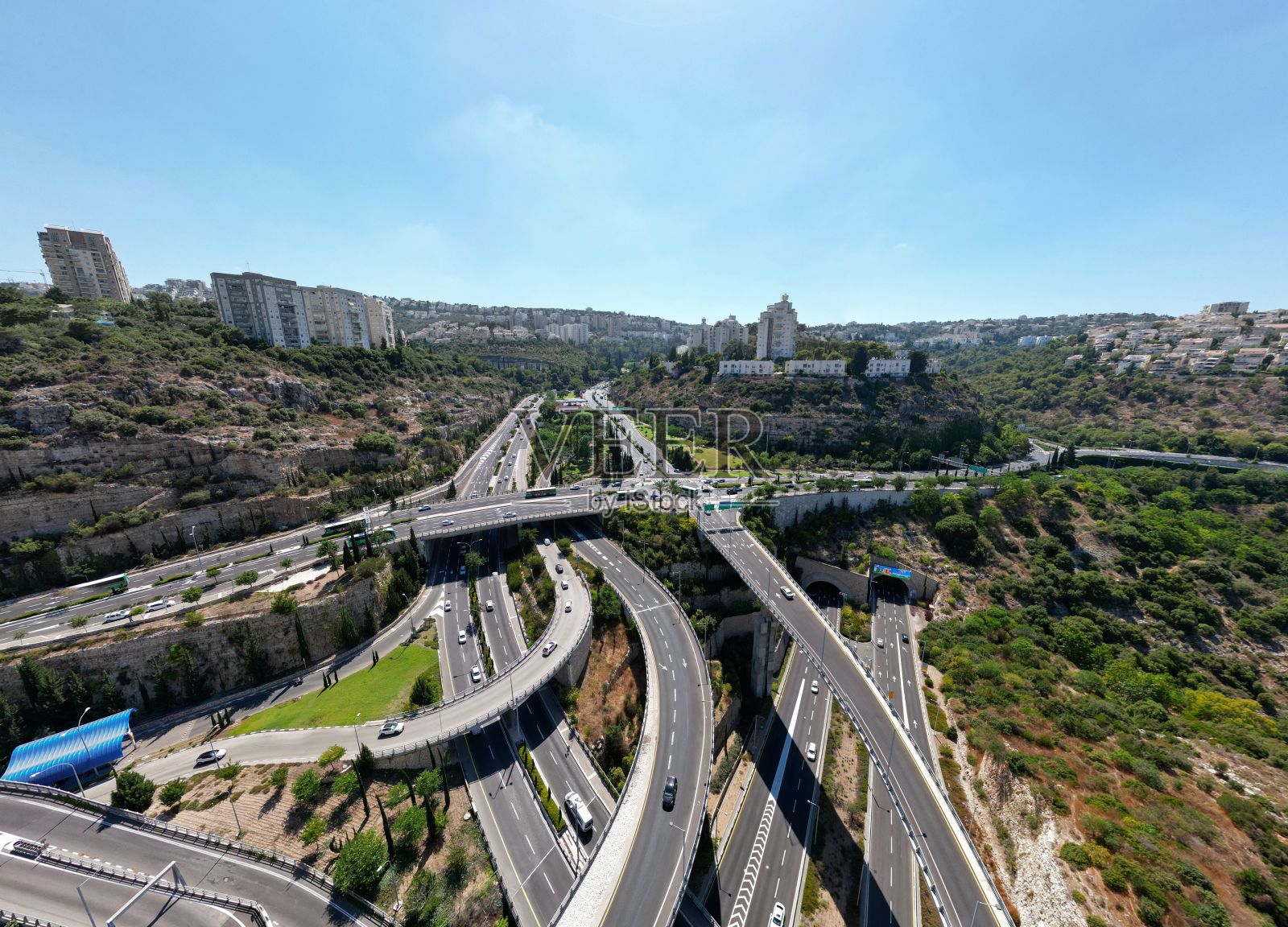 几条柏油路和桥梁的鸟瞰图,周围是山上的住宅楼照片摄影图片
