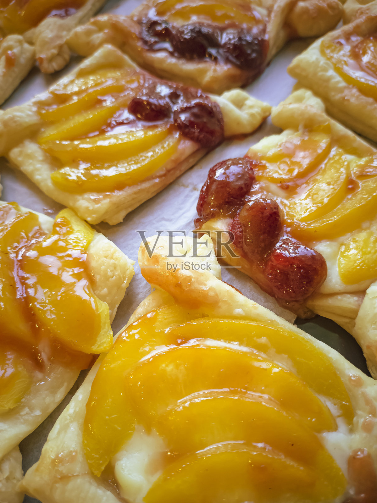 自制的酥皮,红色草莓和芒果,撒上白色糖霜,放在米色木板上。烘焙特写。成品的烹饪背景。香而开胃照片摄影图片