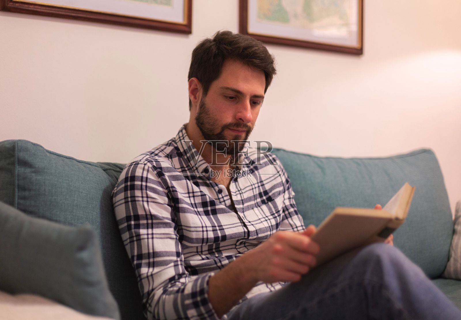 一个白人男子坐在蓝色沙发上看书的风景照片摄影图片