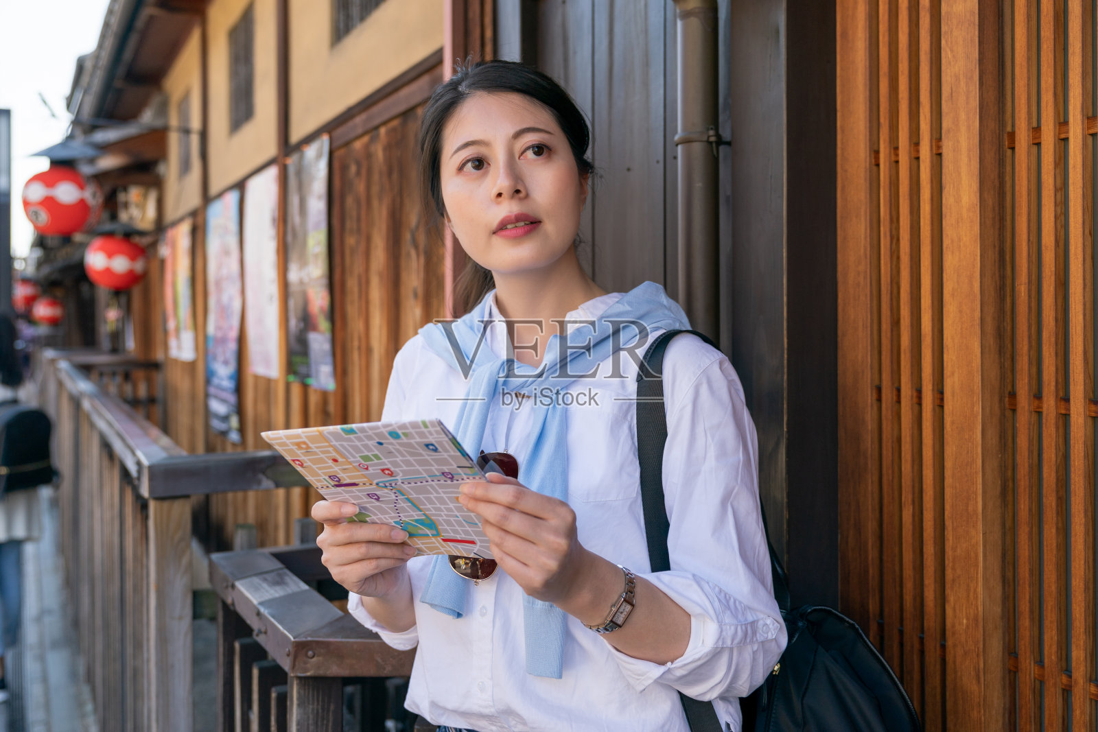 春天,日本京都祇园花之光街,一名亚洲日本女性游客手持城市地图眺望远方照片摄影图片