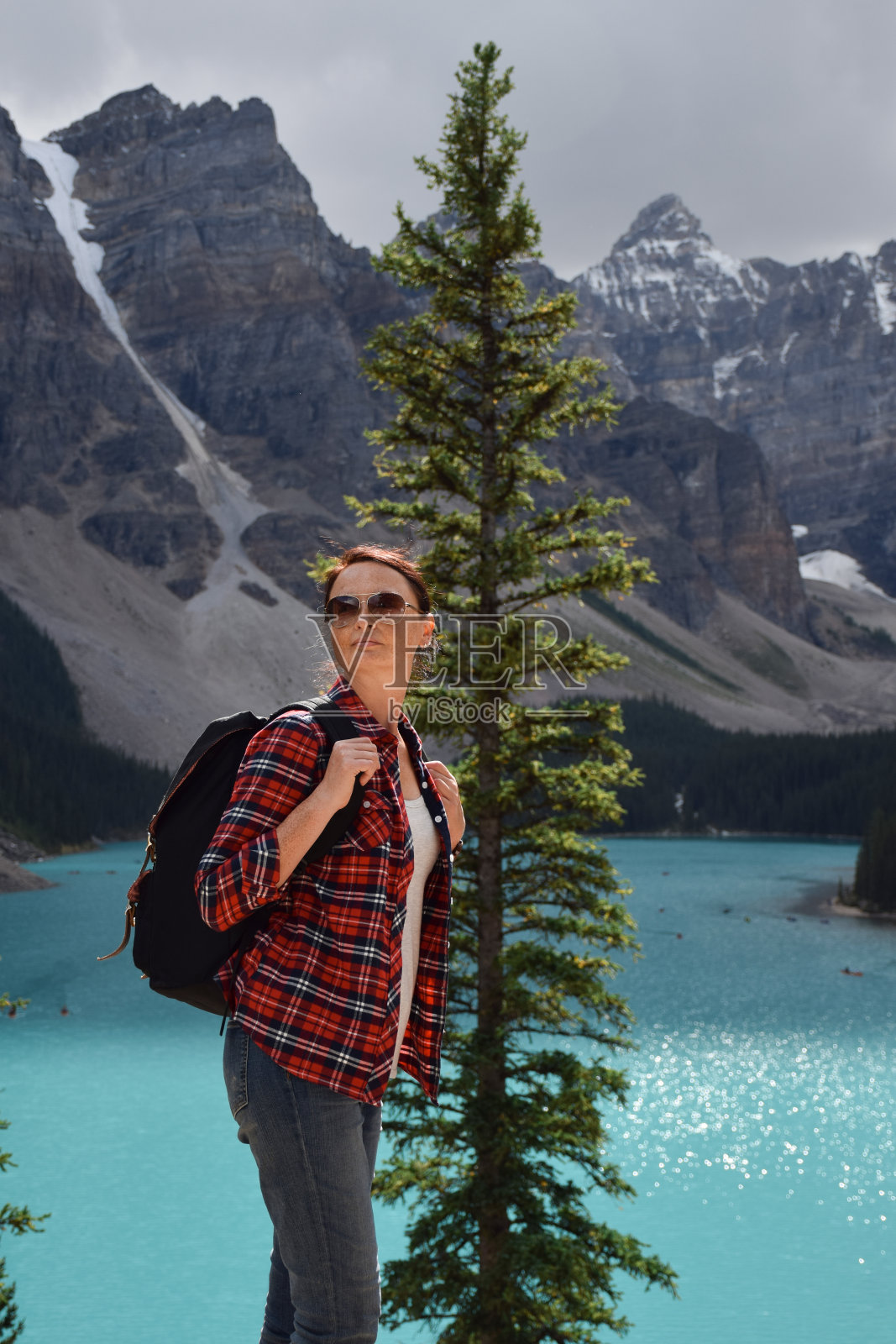 女子背着背包站在美丽的湖泊和山脉前照片摄影图片