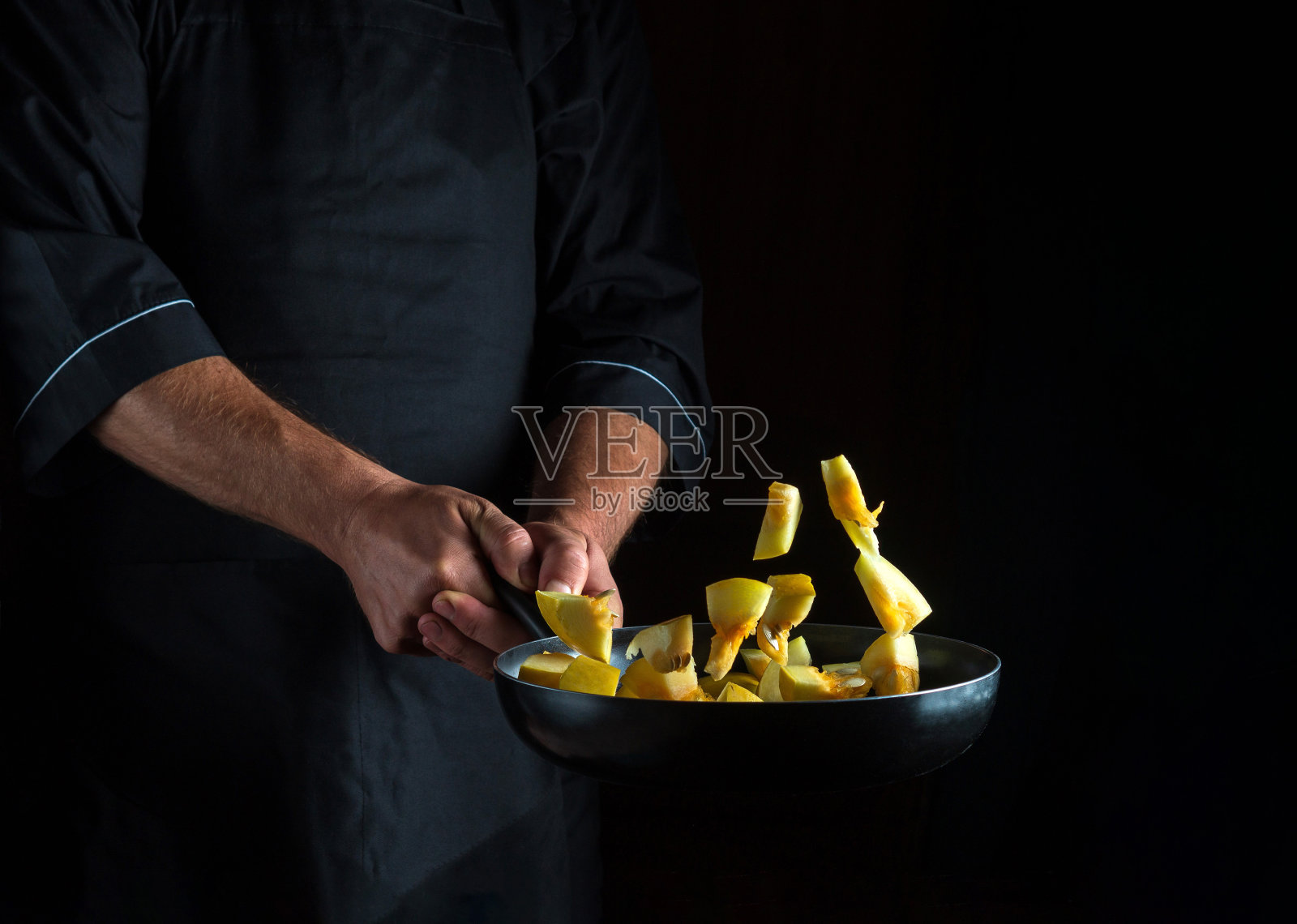 厨师在平底锅里准备西葫芦。在黑暗的背景上烹饪蔬菜和健康的素食。免费广告位照片摄影图片