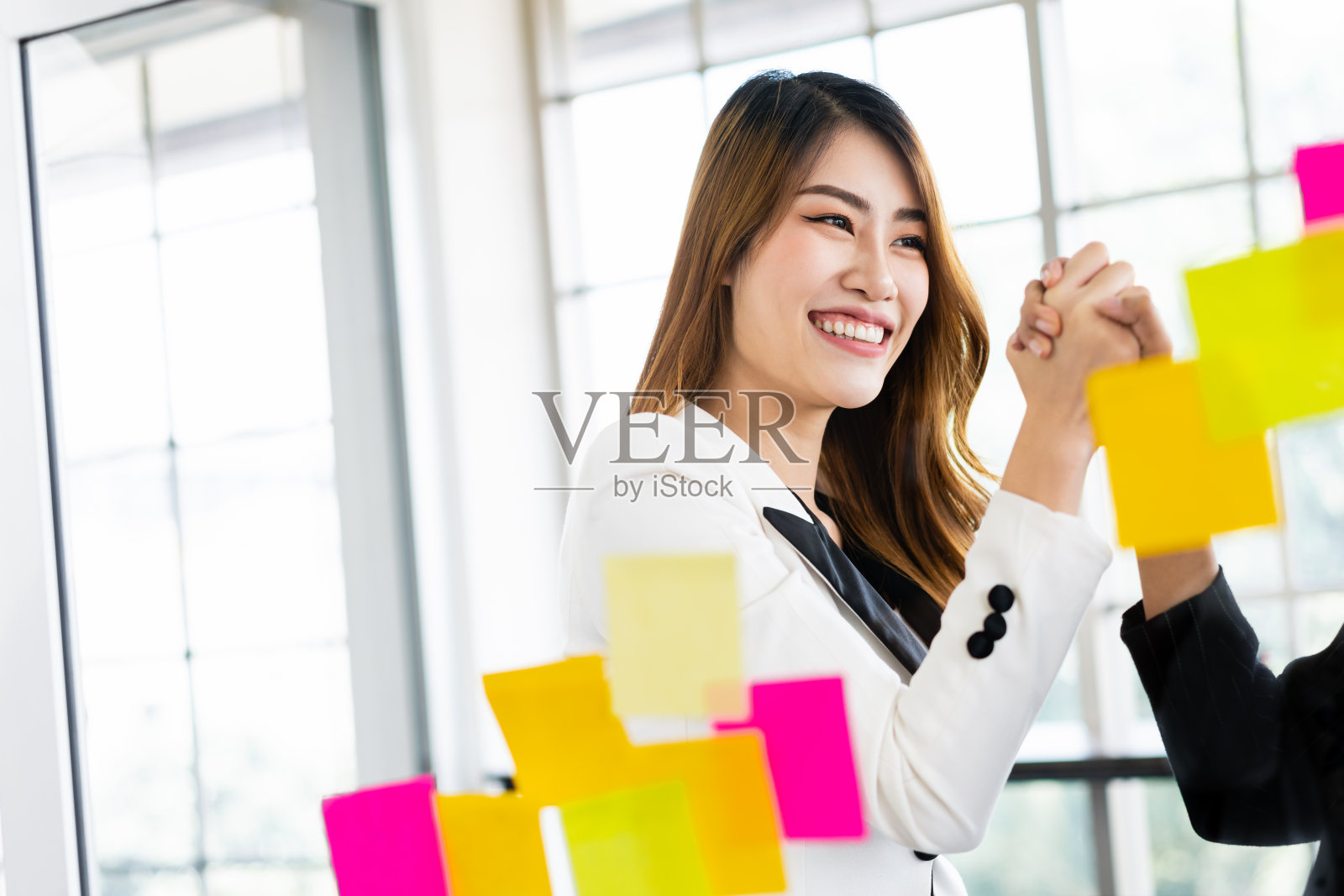 一群成功的亚洲女商人团队。头脑风暴会议,在玻璃墙上贴彩色的便签纸,寻找新的想法。在一家科技初创公司办公室使用敏捷方法。照片摄影图片