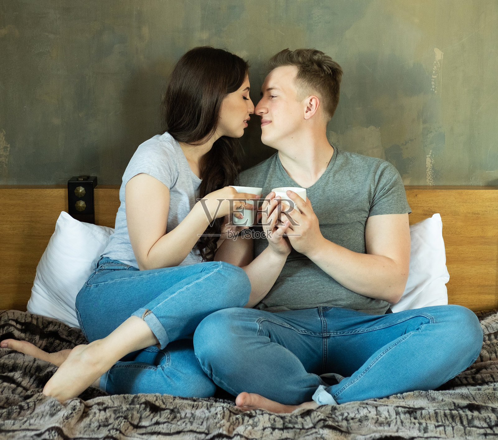 年轻漂亮的情侣早上在床上喝咖啡,生活理念照片摄影图片