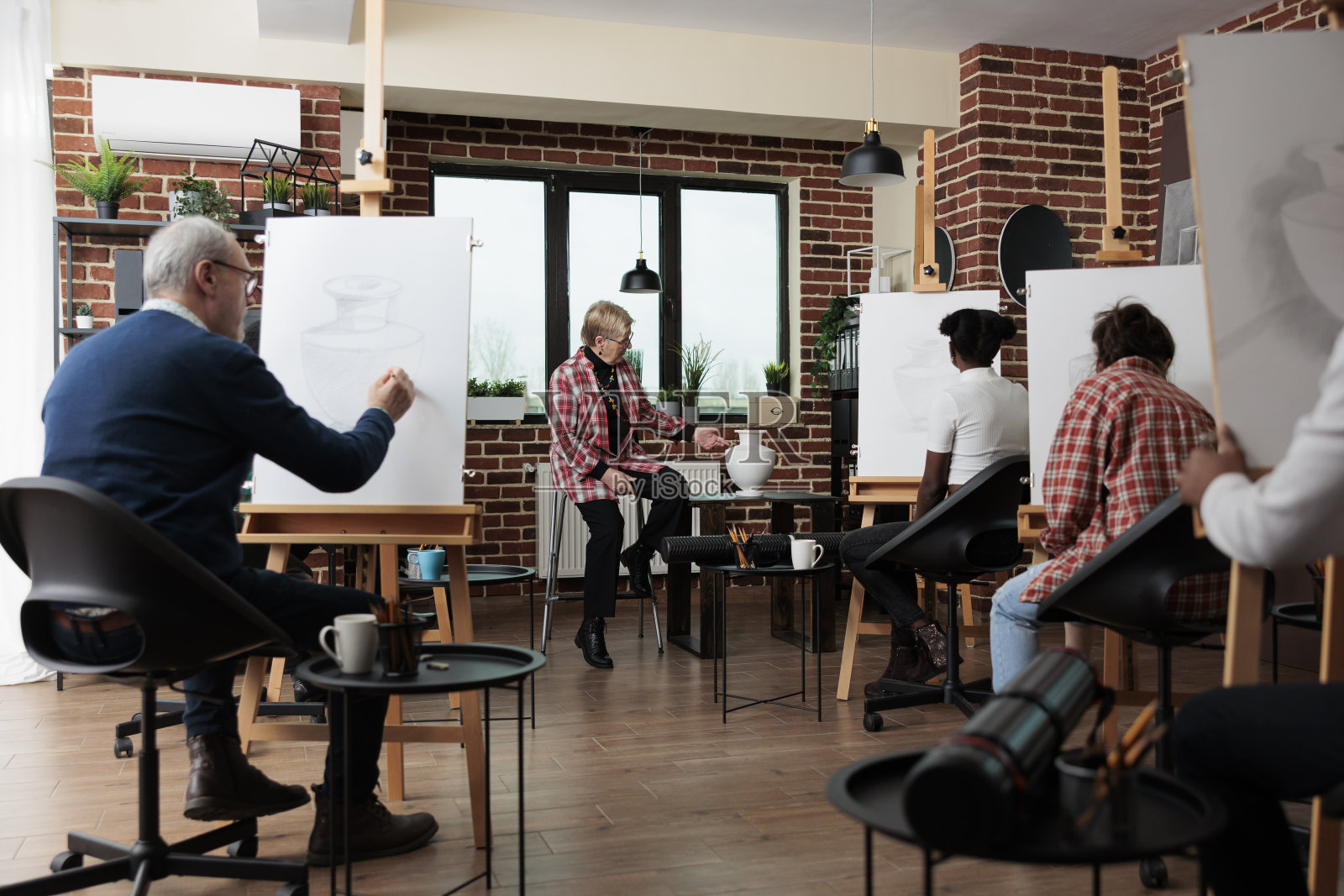 高级教师为多民族艺术学生讲解绘画技巧照片摄影图片