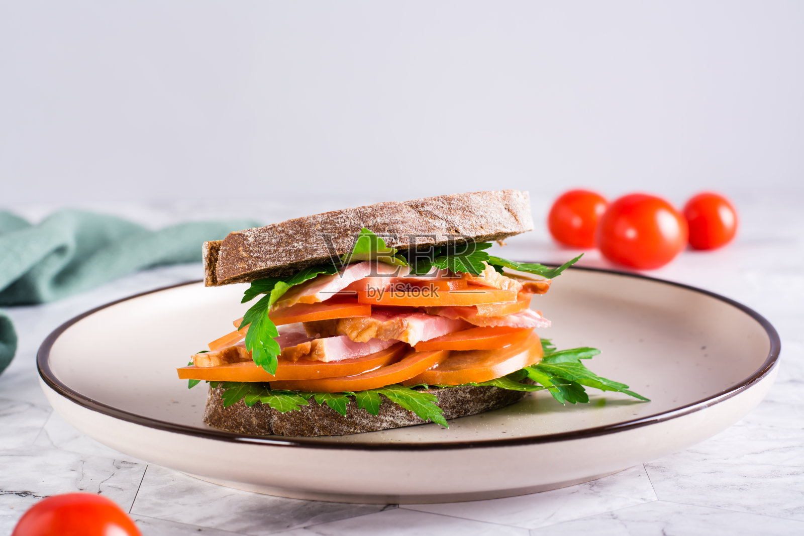 黑麦面包三明治,火腿,西红柿和欧芹放在桌上的盘子里照片摄影图片