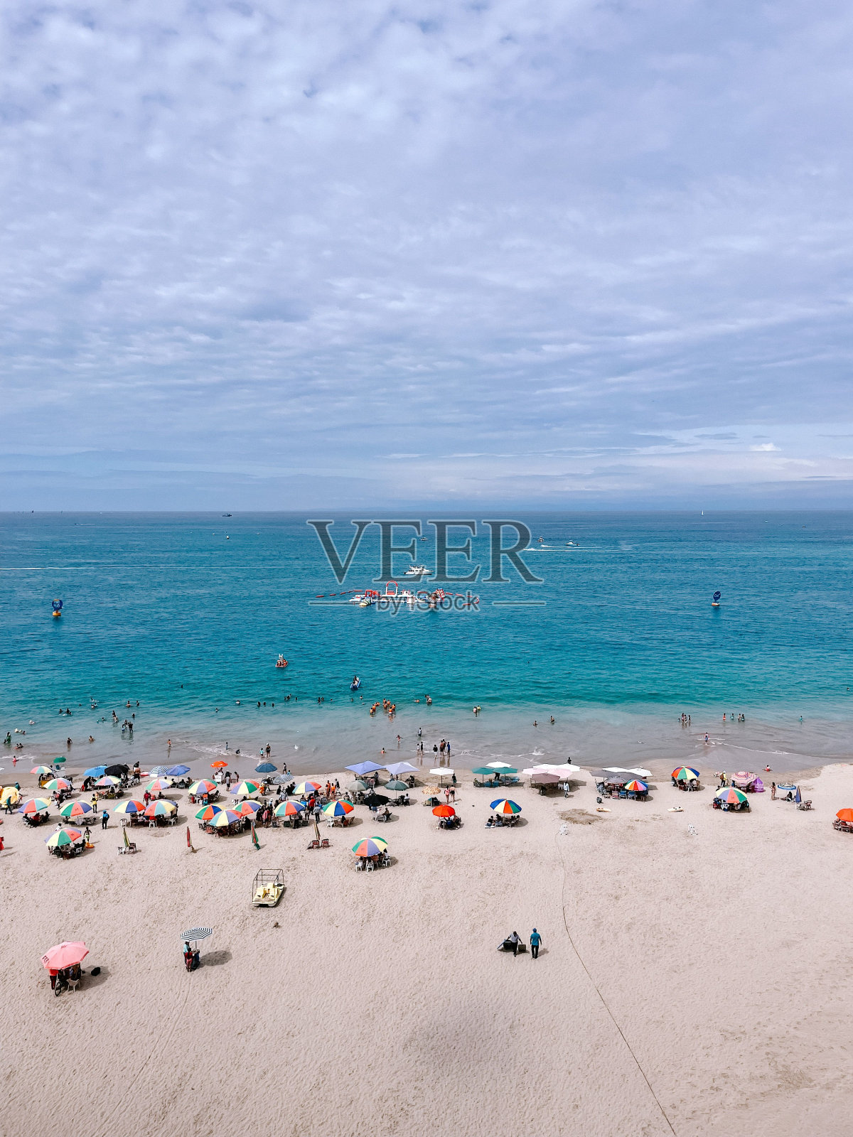 在阳光明媚的日子里,人们在海滩上休息的垂直镜头照片摄影图片