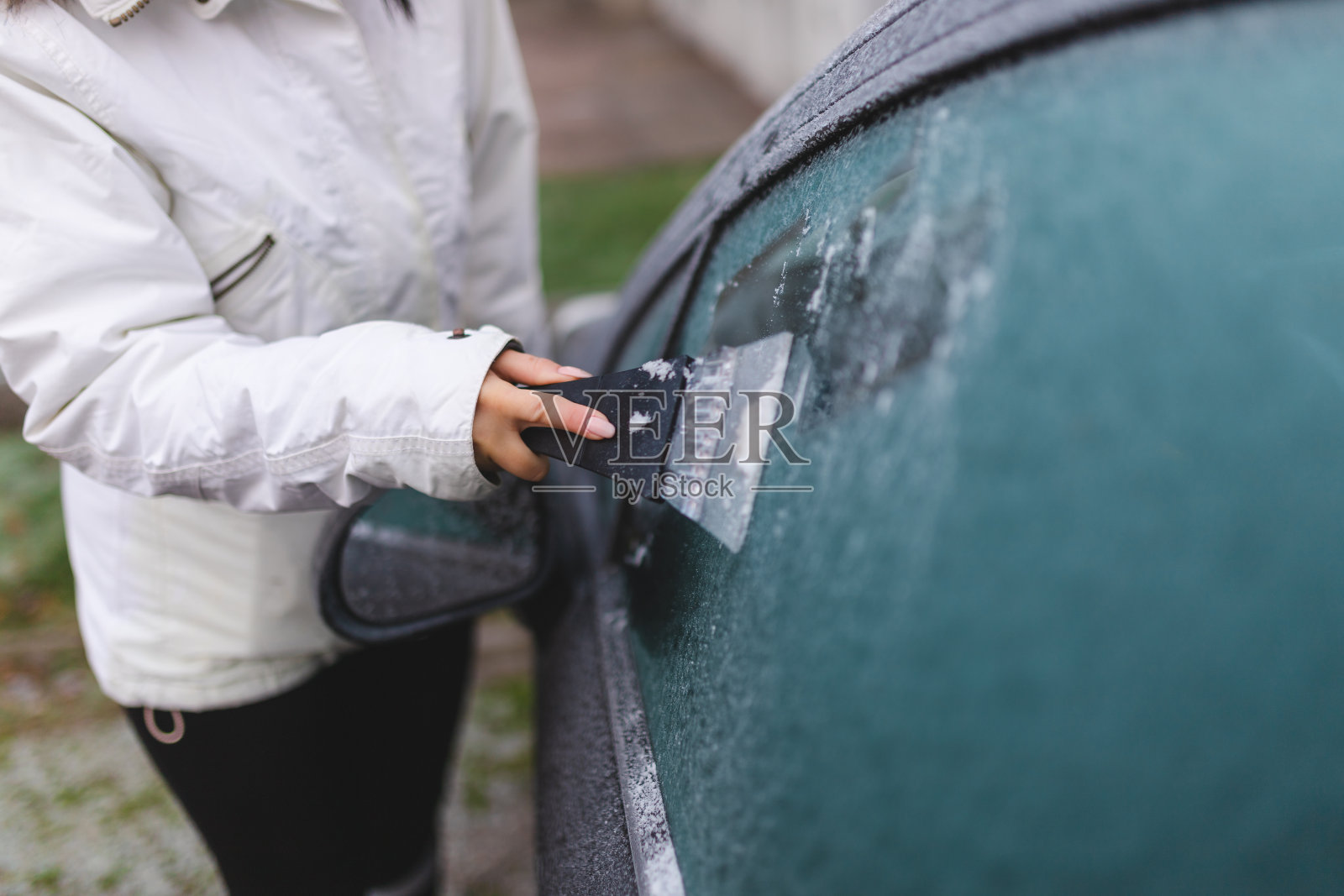 一个年轻女子用刮冰机给车窗除霜的特写镜头照片摄影图片