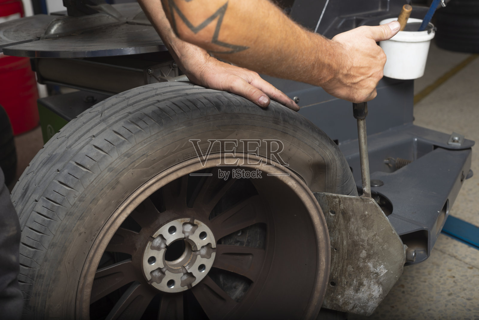 专业机械师的手更换磨损的轮胎。近距离的汽车车轮照片摄影图片