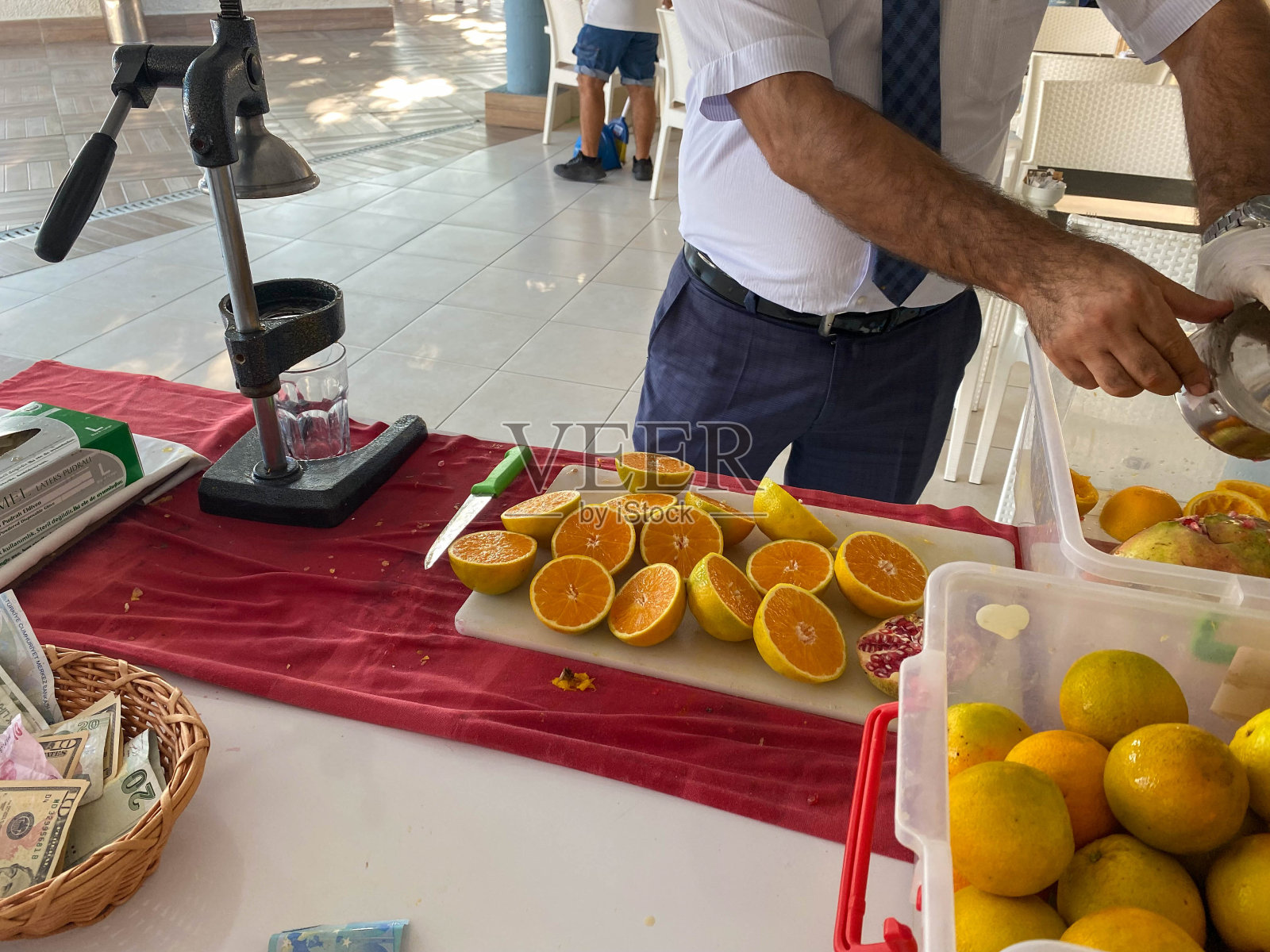 图为,度假期间,在温暖的热带旅游天堂度假胜地,一名男子在一家全包式酒店用手动榨汁机制作鲜榨橙汁照片摄影图片