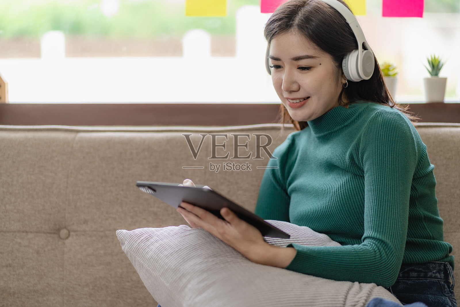 微笑的亚洲妇女使用平板电脑坐在沙发上工作项目在笔记本电脑上看电影,学习,博客,放松,享受在线活动。使用电脑进行在线对话活动照片摄影图片