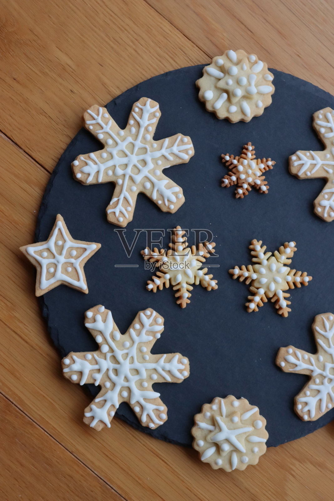 黑色石板盘上星星和雪花形状的节日姜饼饼干照片摄影图片