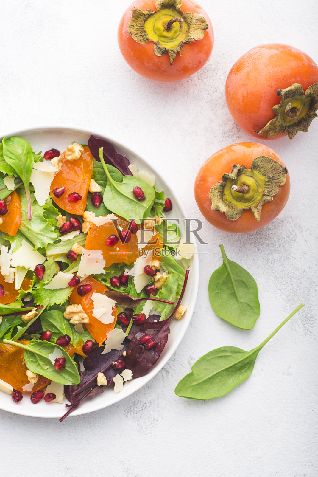 多汁的不寻常沙拉,柿子,石榴,新鲜菠菜,各种叶子,佩克里诺奶酪和核桃。甜咸口味,秋冬沙拉,无麸质食谱。特写镜头照片摄影图片