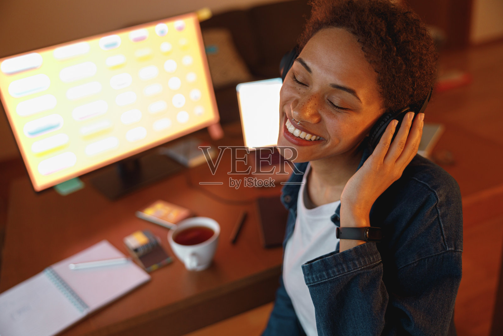 微笑的女性平面设计师喜欢在家庭办公室休息时戴着耳机听音乐照片摄影图片