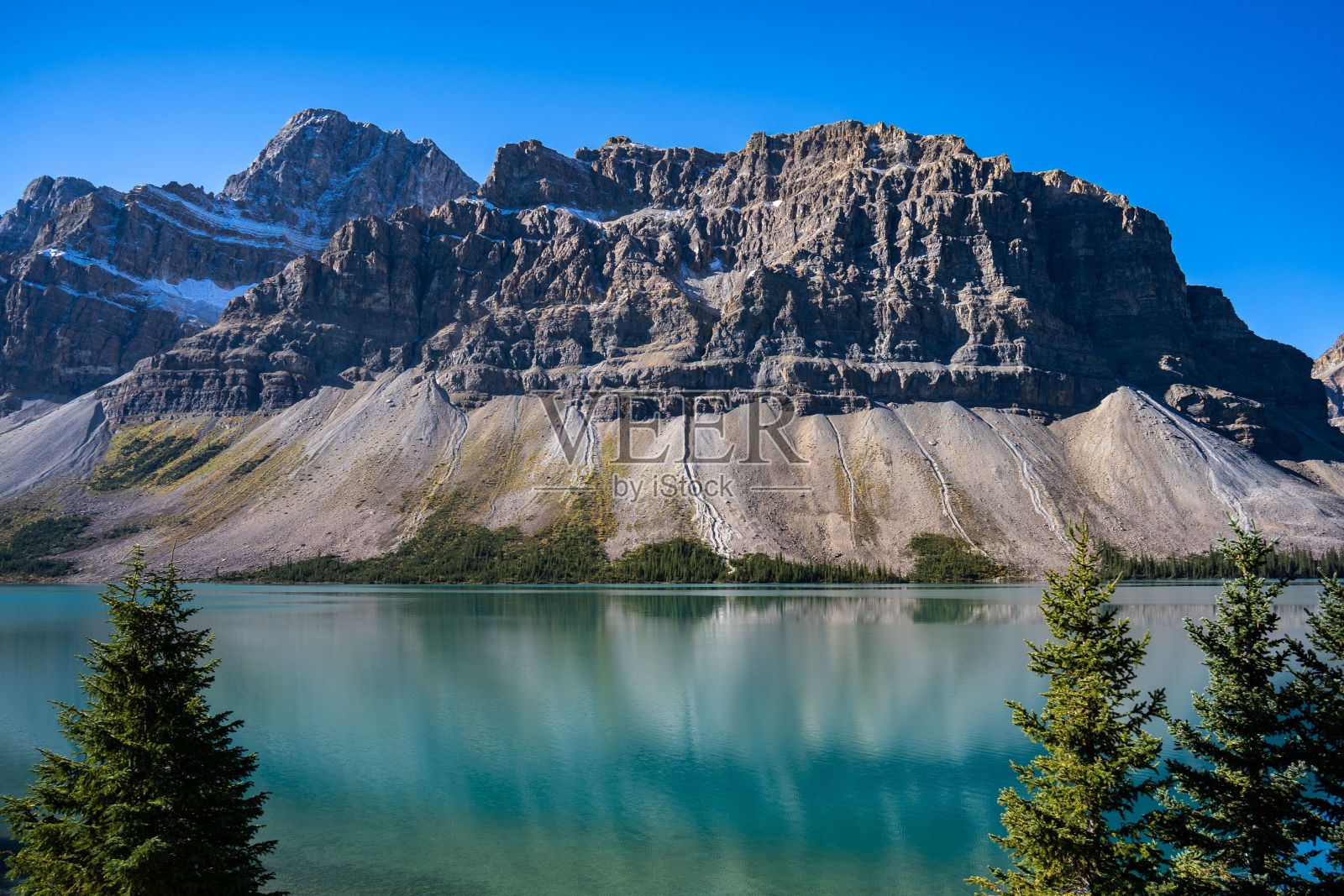 在一个阳光明媚的日子里,山湖的表面,背景是森林和一座岩石山照片摄影图片