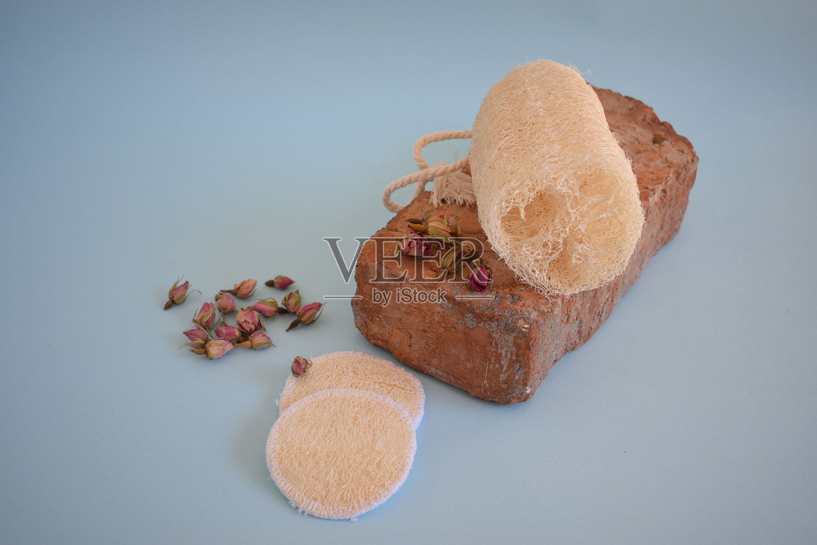 天然丝瓜海绵。用天然海绵在蓝色背景上洗脸。照片摄影图片