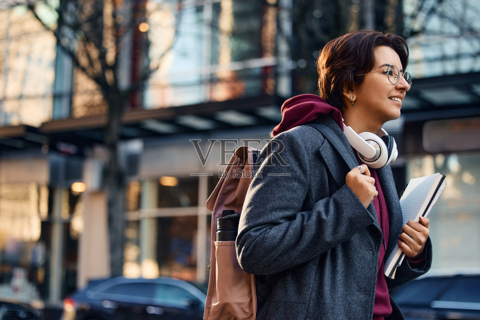 年轻快乐的女人背着背包和笔记本去大学演讲。照片摄影图片