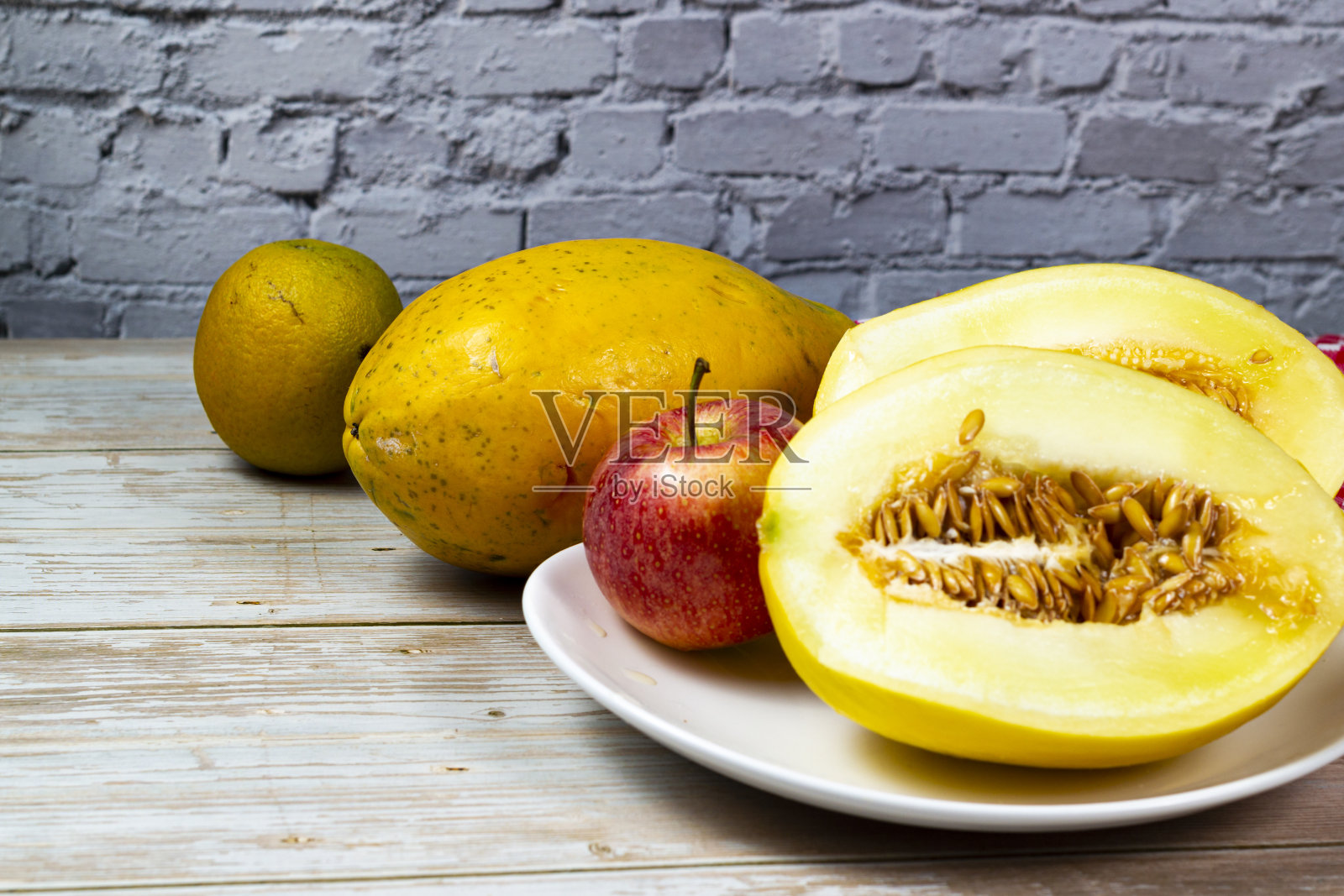 桌上摆满了水果。木桌上放着甜瓜、木瓜和苹果片。选择性聚焦,俯视图。照片摄影图片