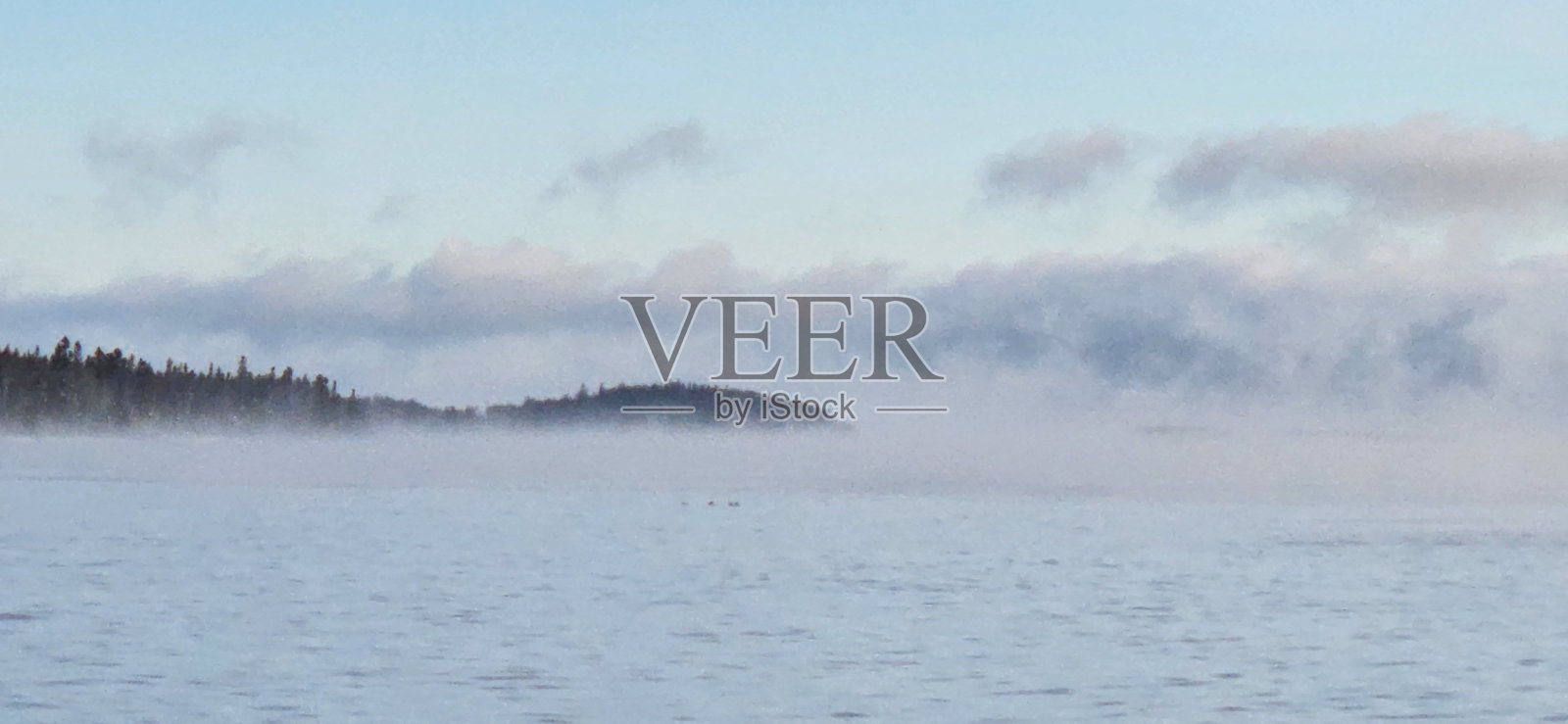 在日出期间,从海滩岸边看到的地平线上可见的雾的风景照片摄影图片