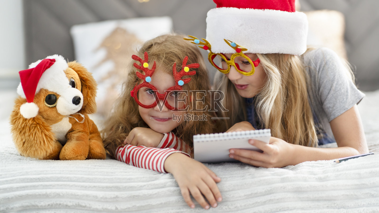 圣诞节期间,孩子们躺在家里的床上照片摄影图片