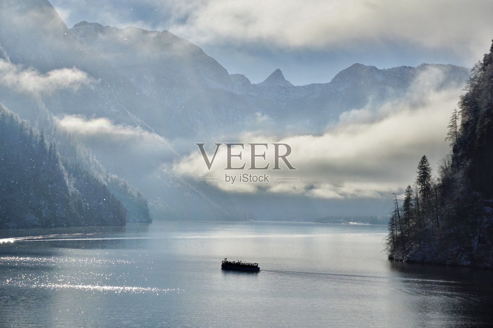 Pier on Lake Königssee in winter. A snow-covered pier on Lake Koenigssee. Berchtesgaden in winter. Upper Bavaria under the snow. An electric large passenger boat sails on the Royal Jako is Lake of Bavaria.照片摄影图片