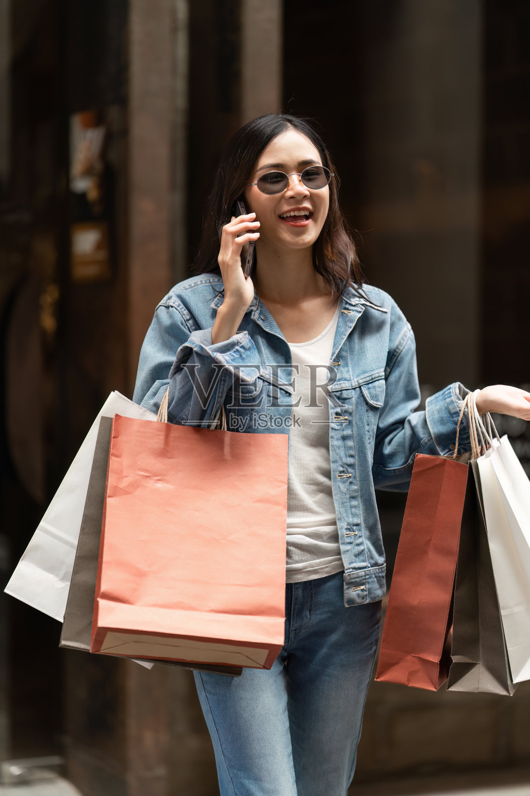 在限时促销期间,亚洲时尚女子拿着购物袋走在购物中心照片摄影图片