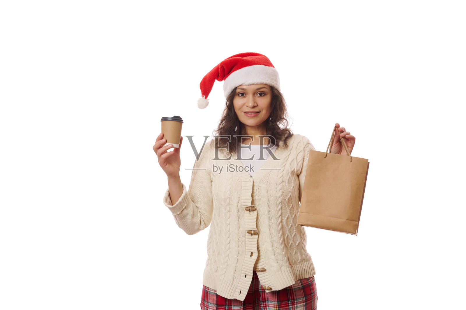迷人的女人戴着圣诞帽,拿着外卖饮料和装着食物的纸袋,在圣诞节使用外卖服务照片摄影图片