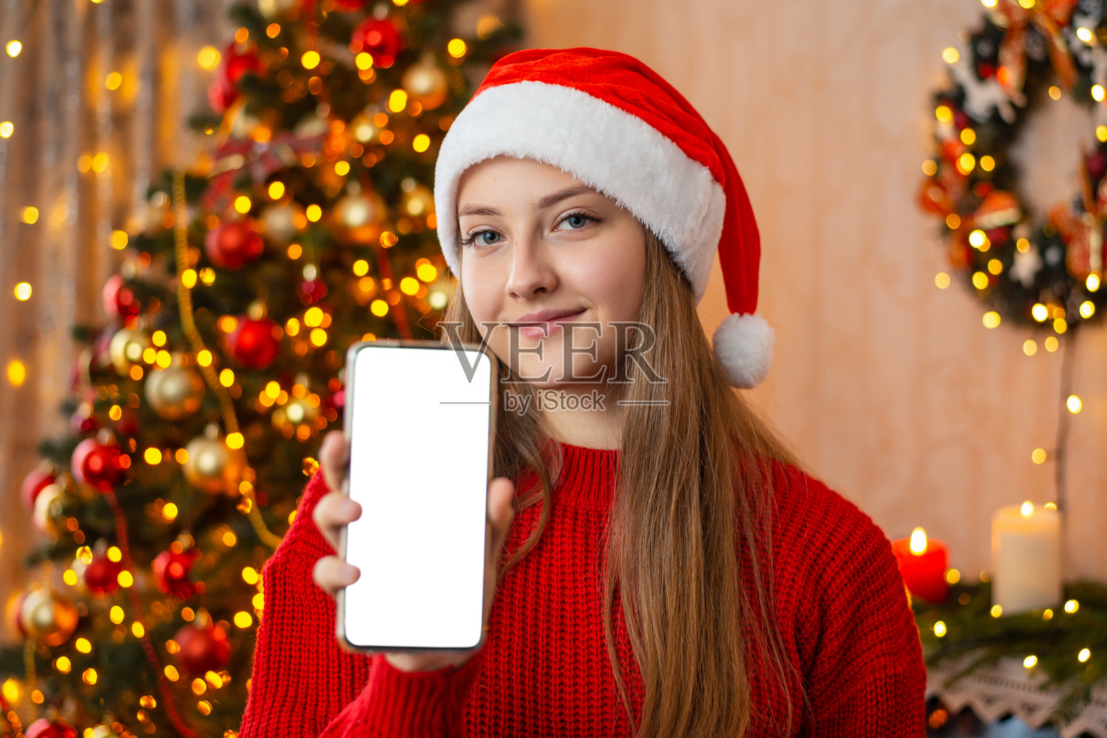 在圣诞节庆祝期间,女孩在家里向相机展示手机屏幕照片摄影图片