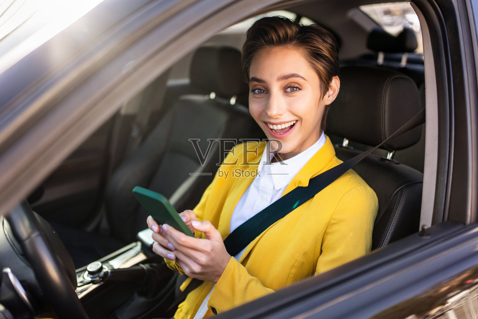 年轻漂亮的短发女子在城市里开车照片摄影图片