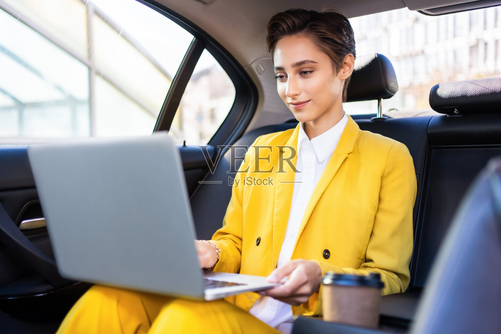 年轻漂亮的短发女子在城市里开车照片摄影图片