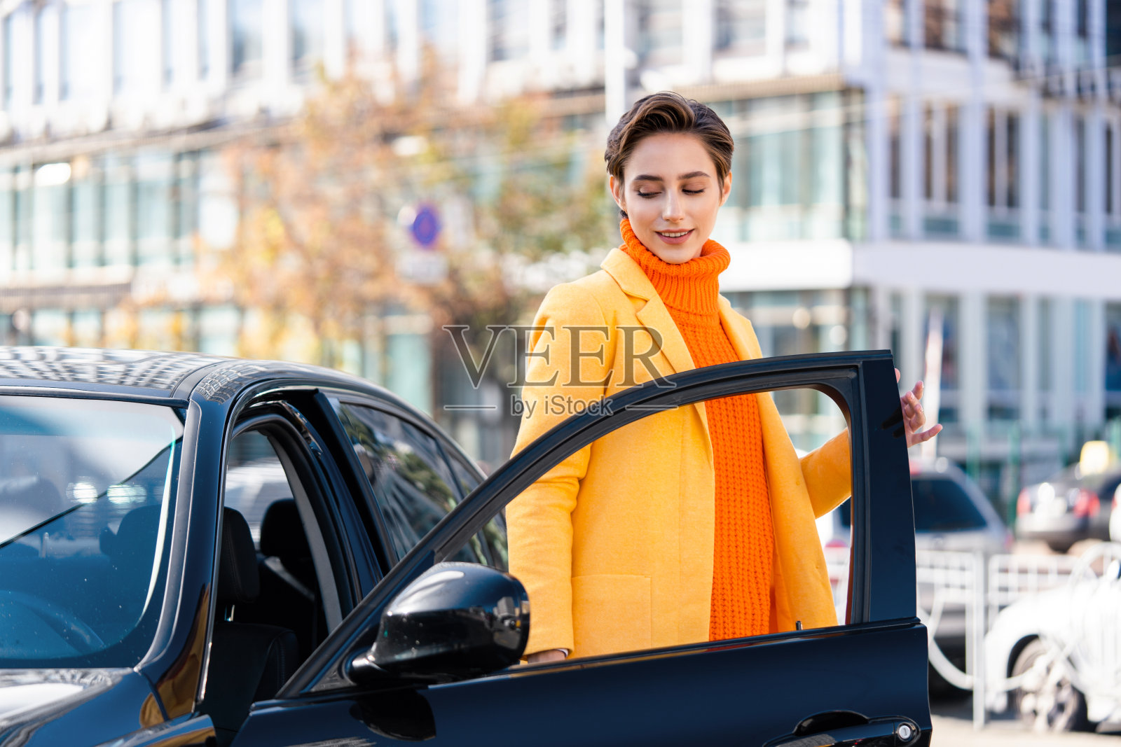 年轻漂亮的短发女子在城市里开车照片摄影图片