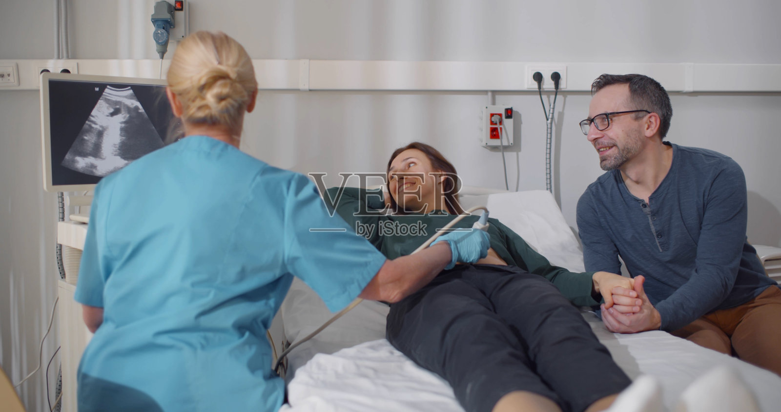 成熟的孕妇夫妇微笑着看着超声扫描仪上的超声结果照片摄影图片