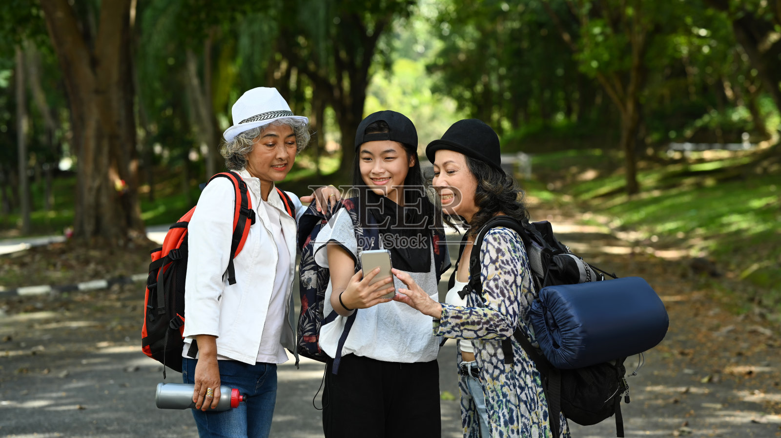亚洲女孩和两名中年妇女在绿色城市公园散步时用智能手机自拍。照片摄影图片