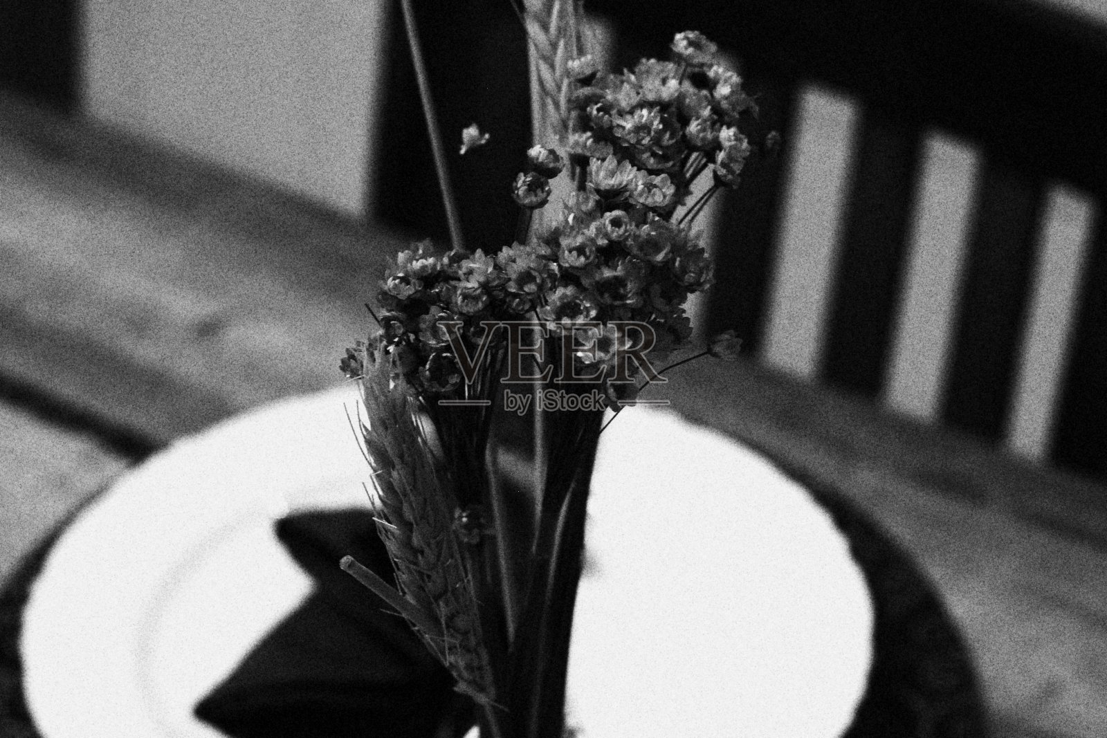 专注于装饰圣诞餐桌的花瓶和小麦。背景中的盘子和椅子模糊不清照片摄影图片