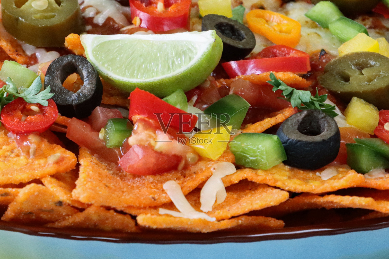 自制的全帧图像,加载玉米片覆盖在融化的马苏里拉奶酪,圣女果,黑橄榄,墨西哥辣椒,高架视图,重点在前景,与酱汁和蘸料照片摄影图片