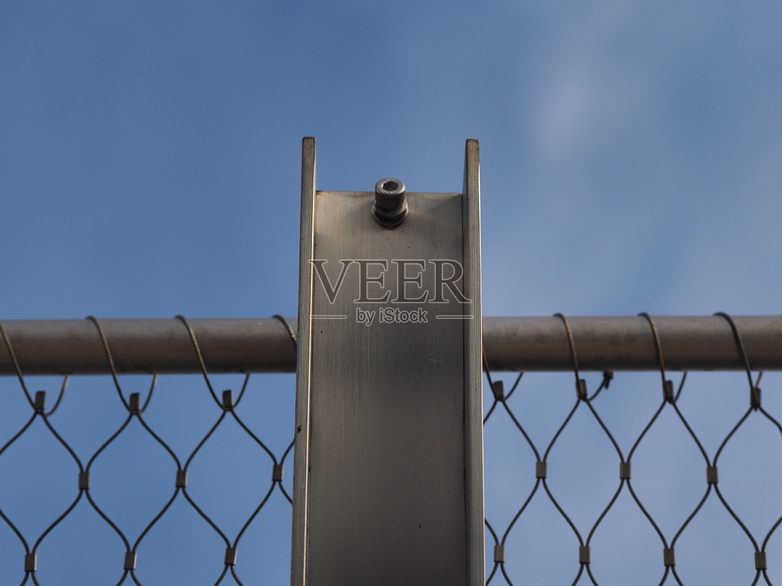 银灰色的铁栅栏,银蓝色的天空,白灰色的云,白光。照片摄影图片