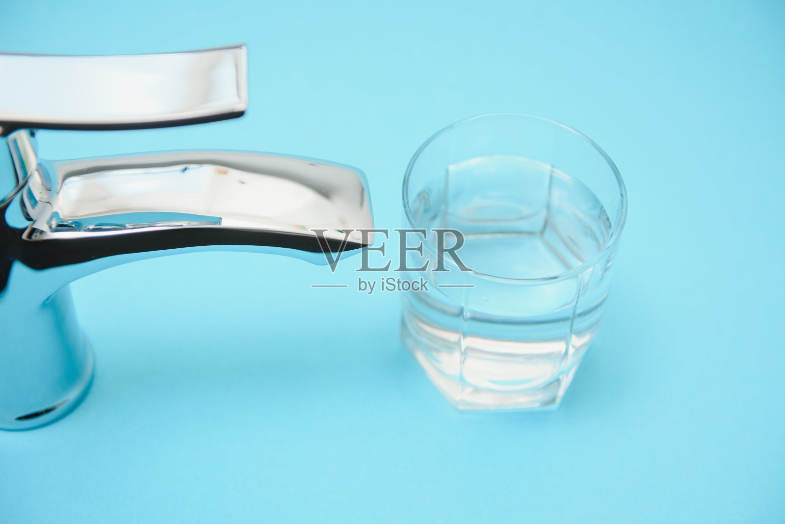 浅蓝色背景上的单手柄水龙头,特写照片摄影图片