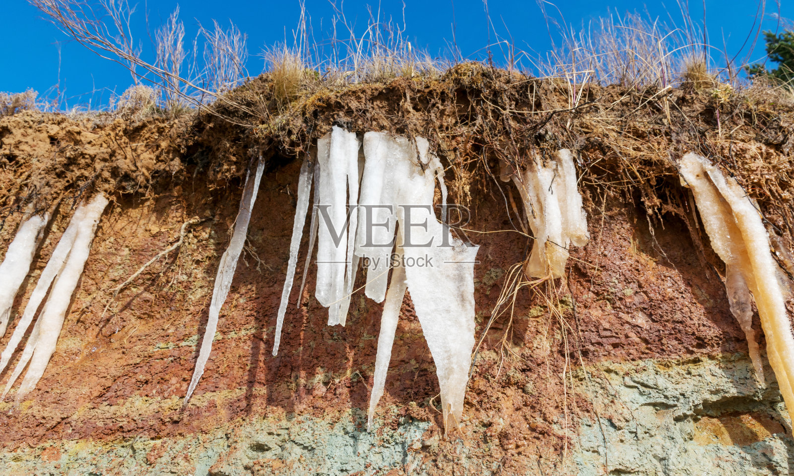 红土墙上的白色冰柱照片摄影图片