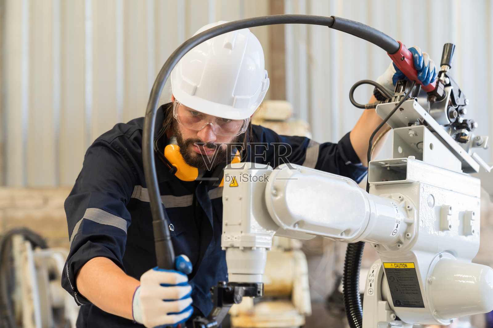男工程师在工厂自动焊接机械臂机旁工作。男技术员在生产线上检查、修理自动焊接机械臂机照片摄影图片