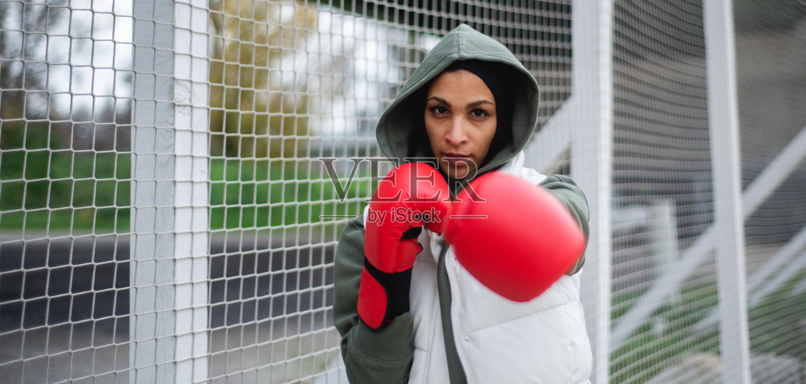 年轻的穆斯林妇女的肖像与拳击手套站在户外的城市。照片摄影图片