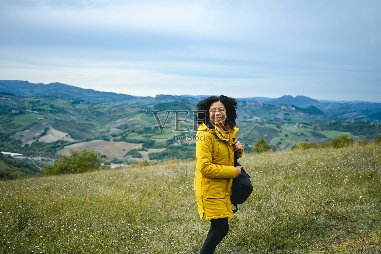 一个中年快乐的女人在草地上远足的肖像。照片摄影图片