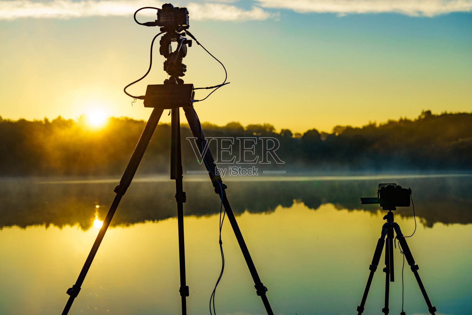 三脚架上的相机在湖面上拍摄日出照片摄影图片