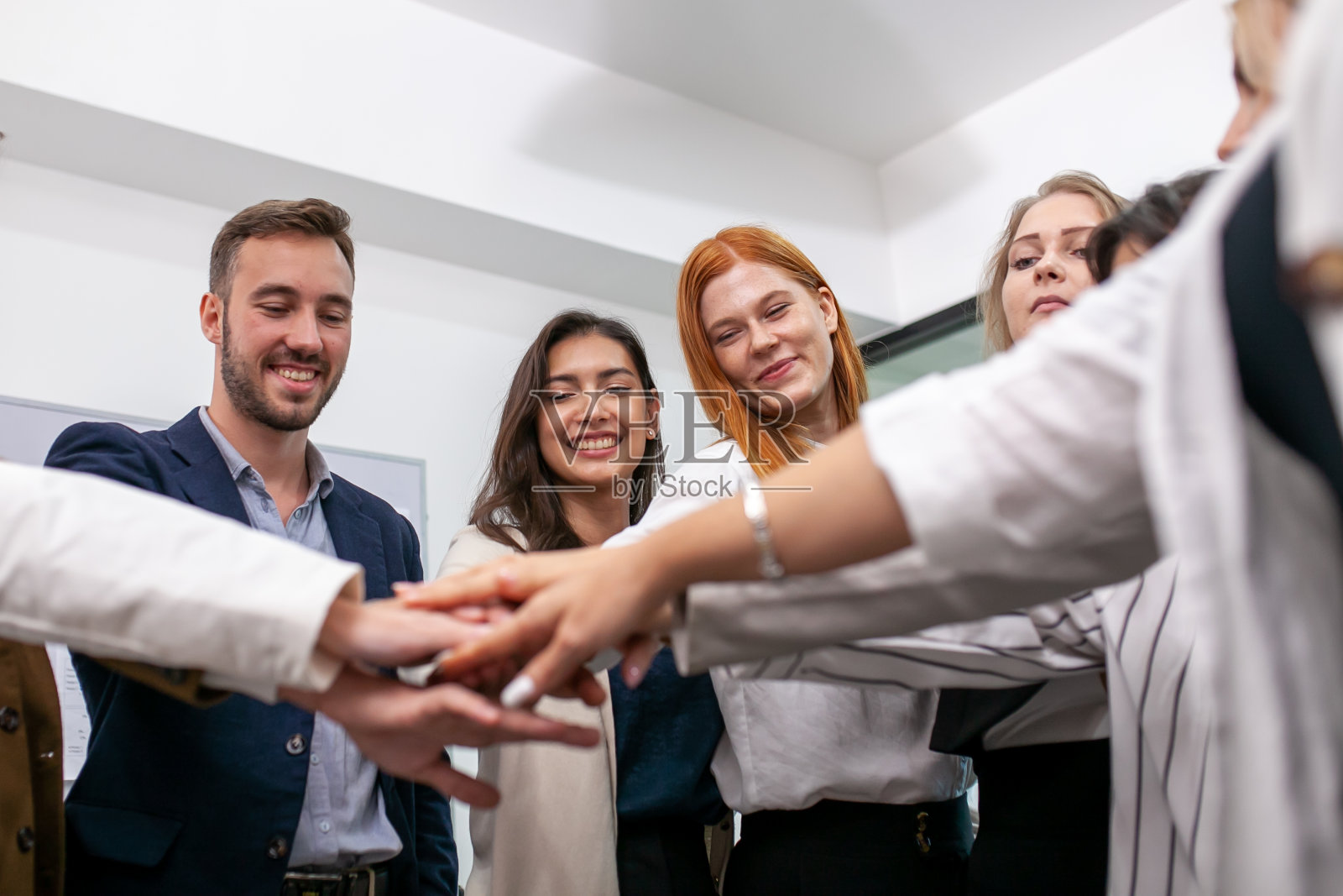 团队合作伙伴业务人员在上班前在办公室击掌,手拉手团结团队,共同完成业务。照片摄影图片