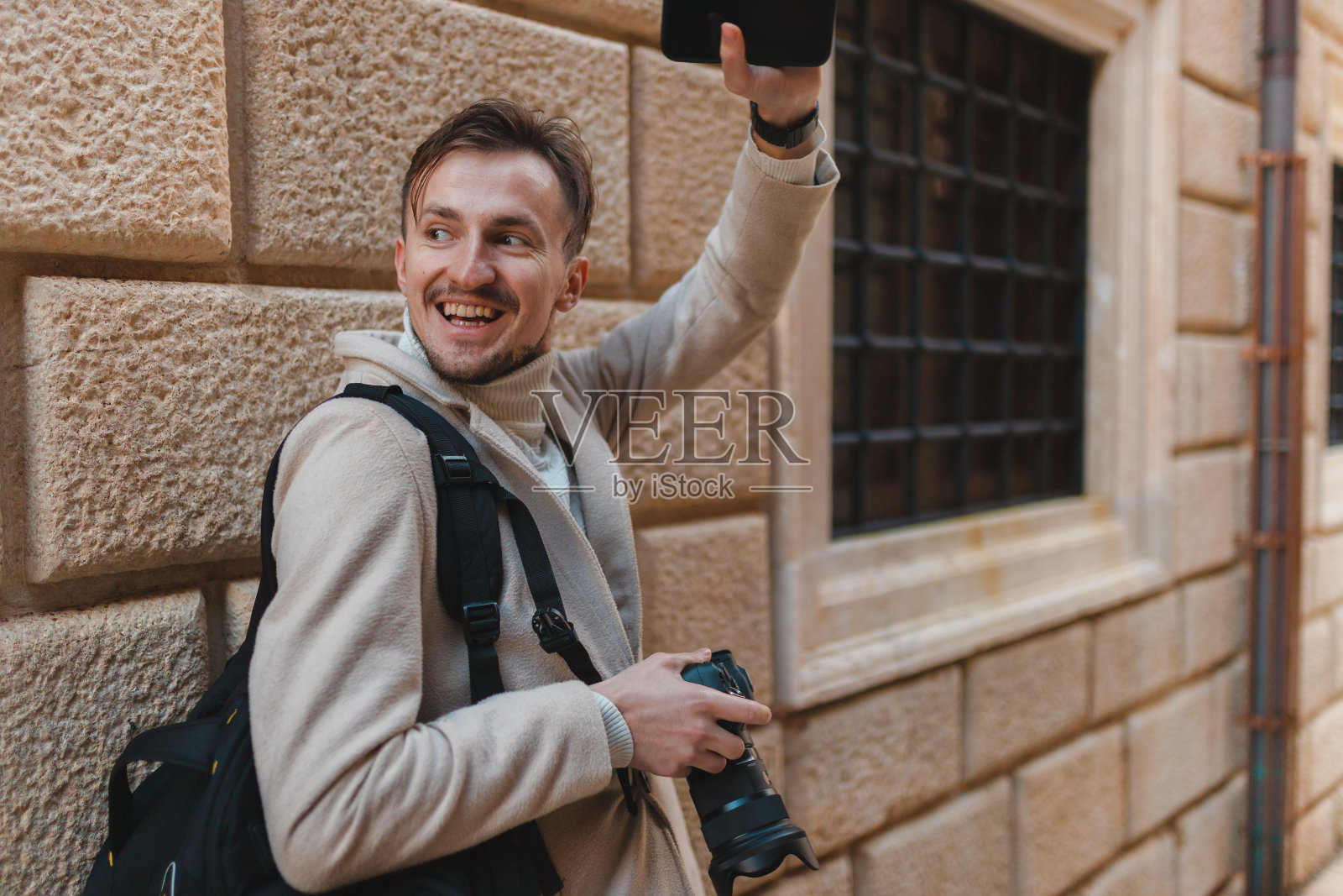 年轻的男性游客拿着相机和手机挥手照片摄影图片