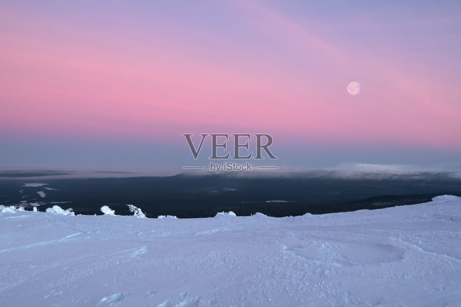 极简的冬季自然景观。满冷的月亮在白雪覆盖的雾坡上。冬季极地夜景。寒冷的冬天。恶劣的北方气候。照片摄影图片