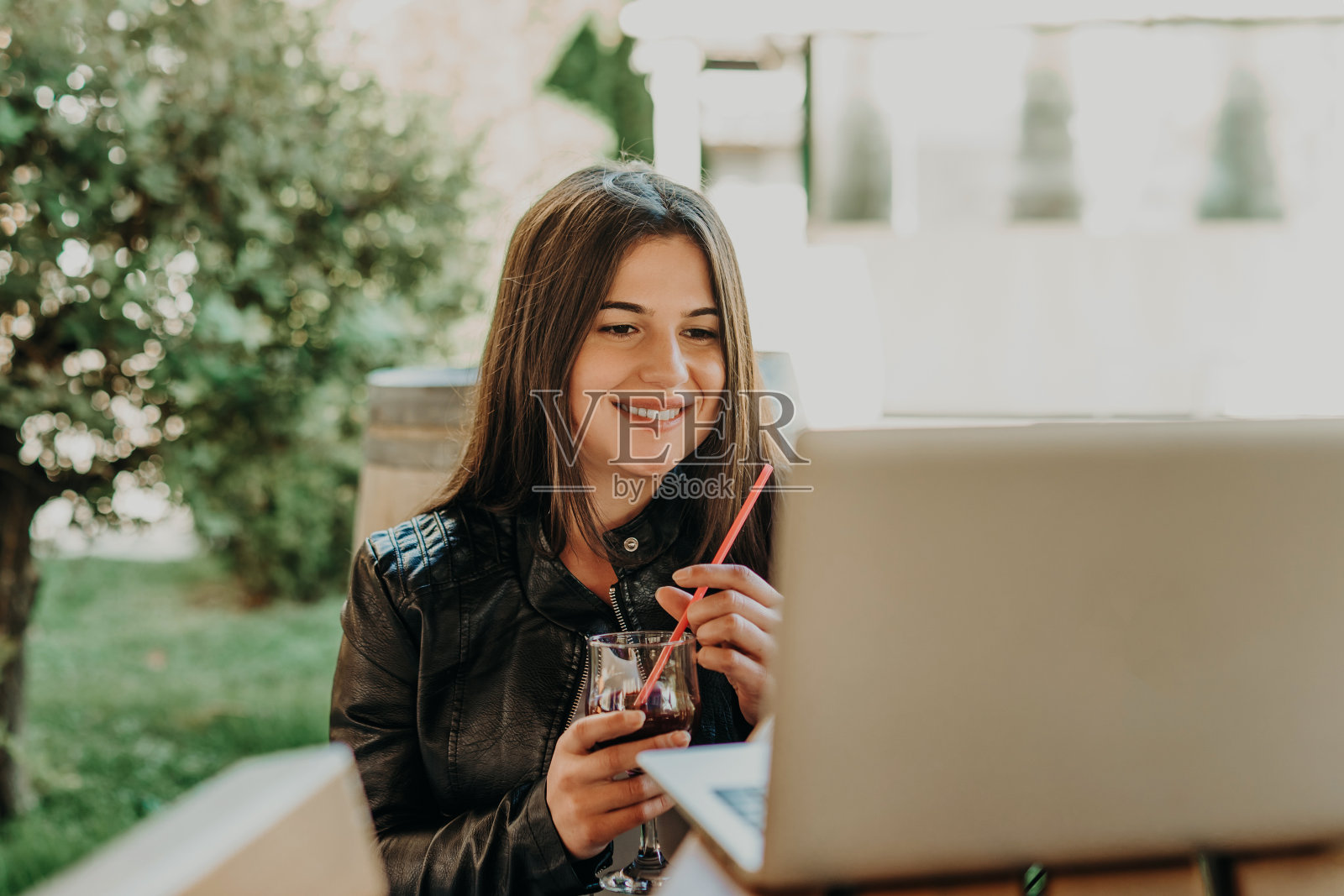 女子在咖啡店边用笔记本电脑边喝果汁照片摄影图片