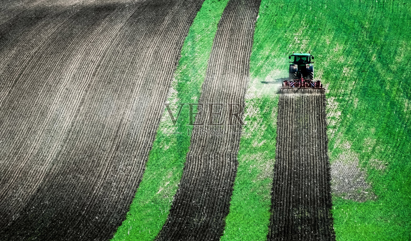 阳光下的大拖拉机在绿地上耕耘照片摄影图片
